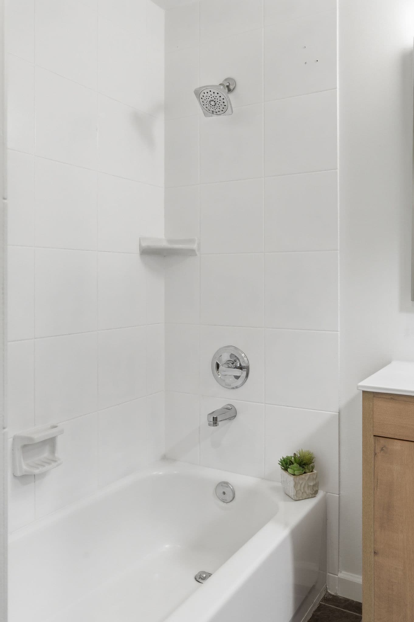 Clean white-tiled shower with newly painted bathroom ceiling and walls