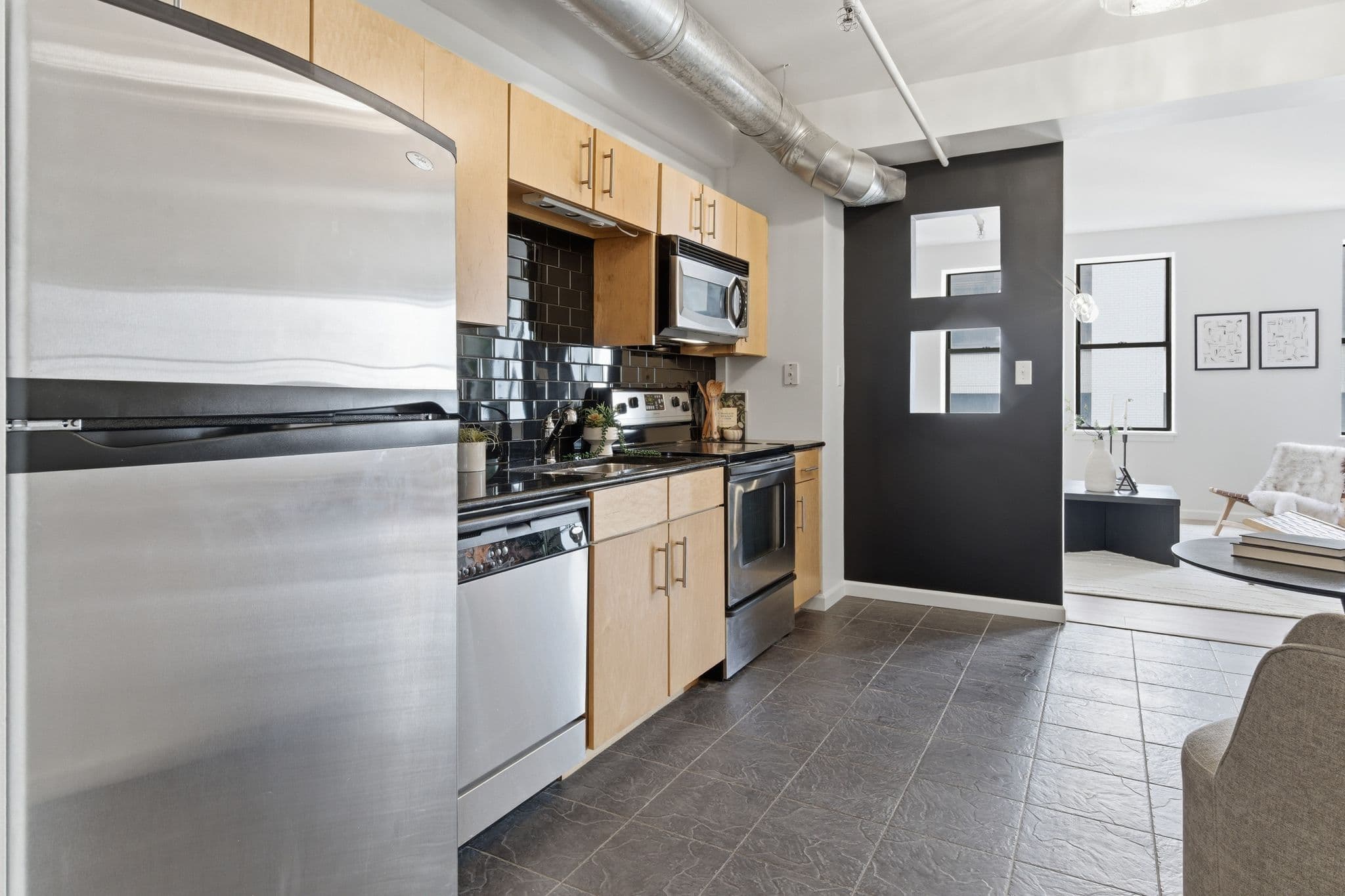Nashville loft kitchen with maple cabinets, stainless appliances, and a painted dark accent wall
