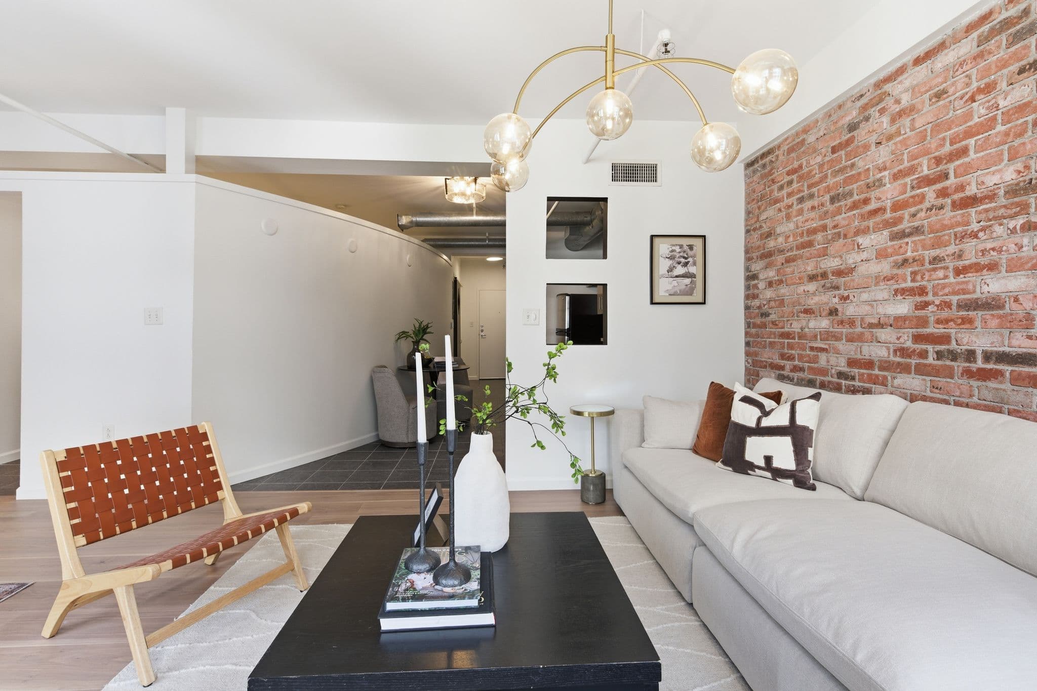 Loft living room with a curved white painted wall, exposed brick, and modern light fixtures